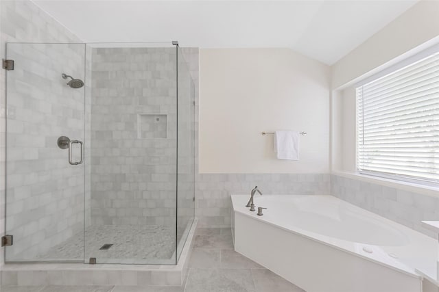 full bathroom featuring a shower stall, a bath, and a wainscoted wall