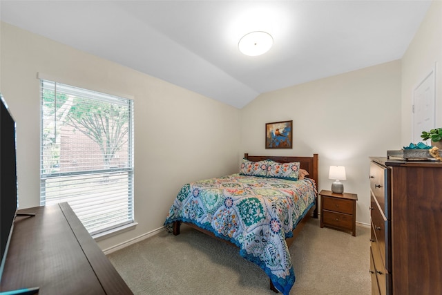 bedroom with vaulted ceiling, baseboards, and light colored carpet