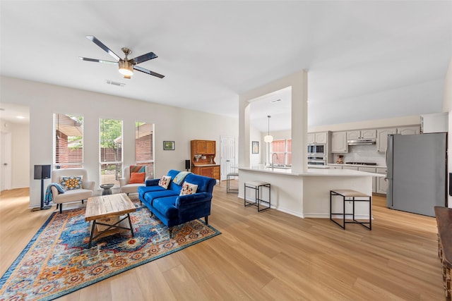 living room featuring light wood-style floors, visible vents, and a wealth of natural light