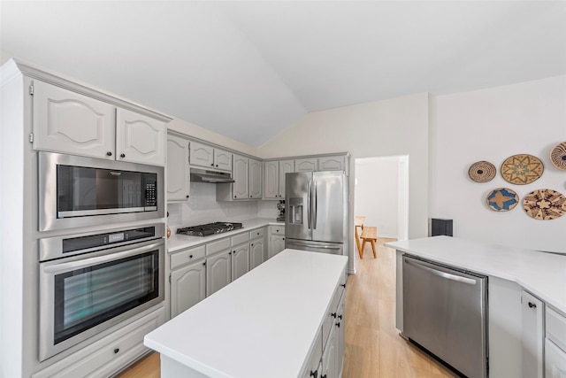 kitchen with vaulted ceiling, under cabinet range hood, appliances with stainless steel finishes, and light wood-style flooring