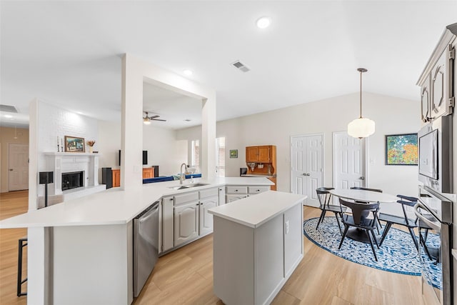 kitchen with a ceiling fan, a sink, light wood-style flooring, stainless steel appliances, and light countertops