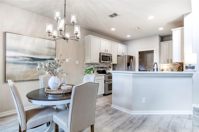 8741 Bigelow Dr, Plano, TX 75024 - kitchen featuring appliances with stainless steel finishes, tasteful backsplash, light wood-type flooring, a chandelier, and white cabinets
