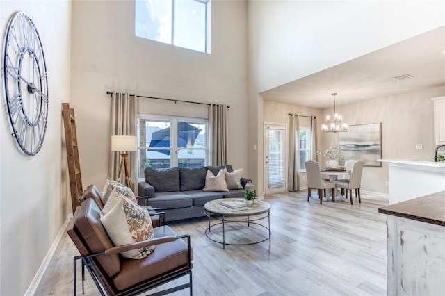 8741 Bigelow Dr, Plano, TX 75024 - living room featuring a chandelier, light wood-style flooring, baseboards, healthy amount of natural light, and a high ceiling