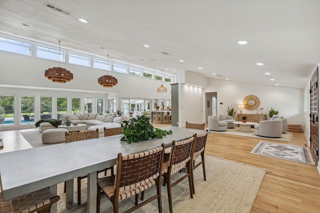 dining space with recessed lighting, wood finished floors, visible vents, and a high ceiling