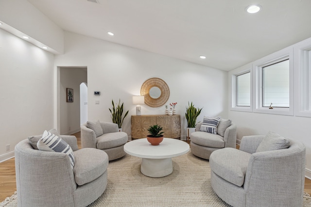 living area with arched walkways, vaulted ceiling, wood finished floors, and recessed lighting