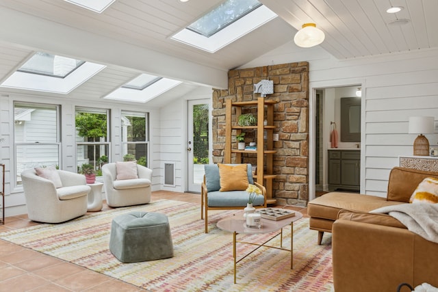 living area with wooden walls, light tile patterned flooring, and vaulted ceiling with skylight