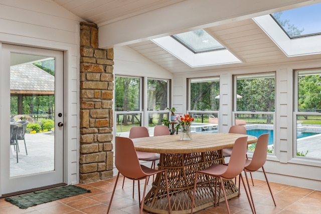 sunroom / solarium featuring tile patterned floors and lofted ceiling with skylight