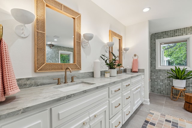 bathroom with tile patterned flooring, a sink, double vanity, and tile walls