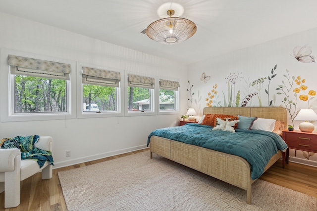 bedroom with baseboards, wood finished floors, and multiple windows