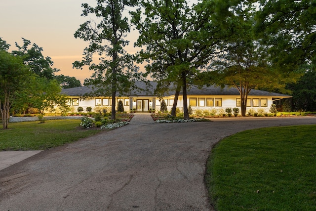 ranch-style home with a front lawn, french doors, and curved driveway