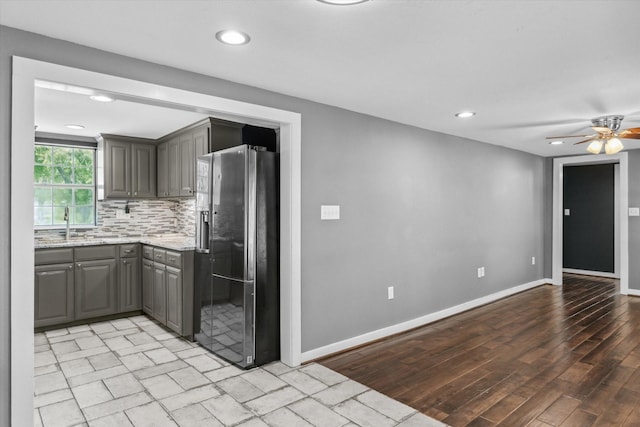 kitchen with stainless steel refrigerator with ice dispenser, gray cabinetry, recessed lighting, and backsplash