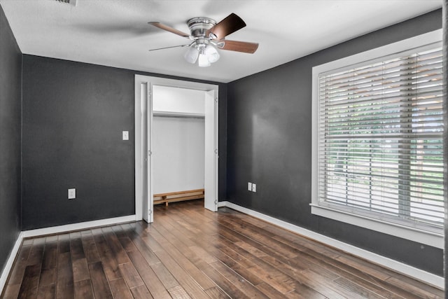unfurnished bedroom featuring a ceiling fan, baseboards, and dark wood-style flooring