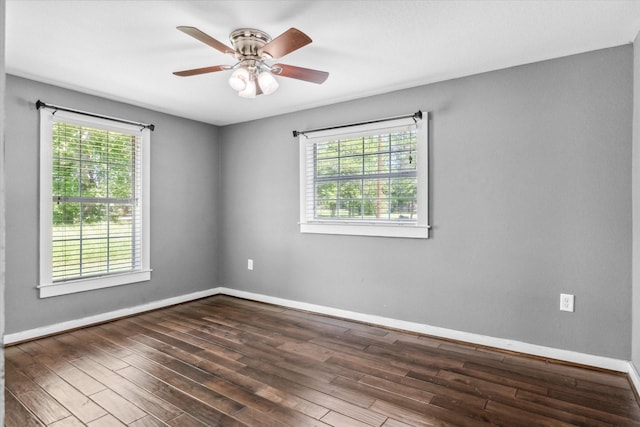 unfurnished room featuring baseboards, dark wood-type flooring, and plenty of natural light