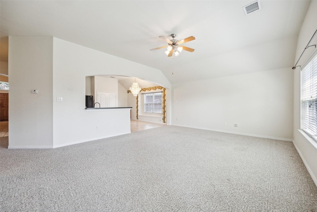 unfurnished living room featuring visible vents, light colored carpet, a healthy amount of sunlight, and ceiling fan with notable chandelier