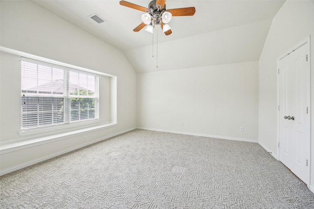 empty room featuring lofted ceiling, a ceiling fan, visible vents, and carpet floors