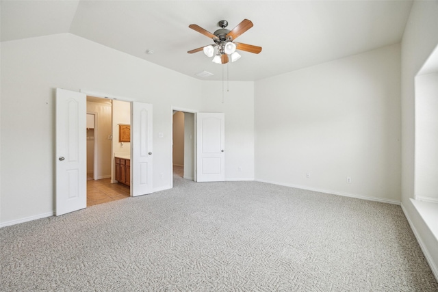 unfurnished bedroom with ensuite bathroom, baseboards, vaulted ceiling, and light colored carpet