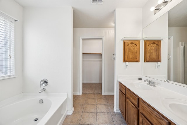 bathroom with a bath, a healthy amount of sunlight, a sink, and double vanity