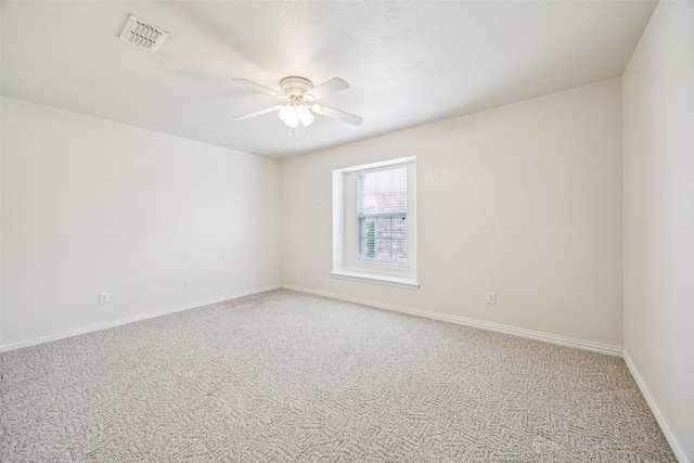 empty room featuring light carpet, baseboards, visible vents, and ceiling fan