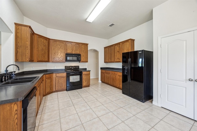 kitchen with dark countertops, visible vents, a sink, arched walkways, and black appliances