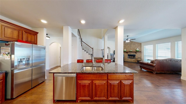 916 Sunset Haven Dr, Little Elm, TX 75068 - kitchen featuring stainless steel appliances, ceiling fan, arched walkways, dark wood-style floors, and dark stone counters