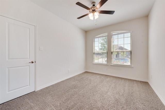carpeted spare room featuring a ceiling fan and baseboards