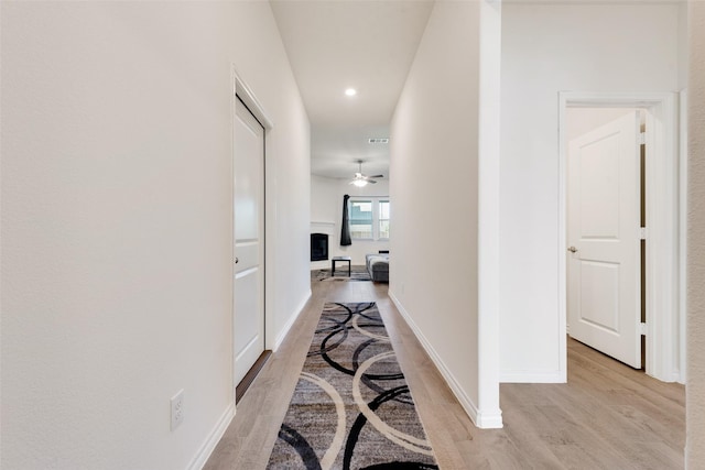 hall featuring recessed lighting, light wood-style flooring, visible vents, and baseboards
