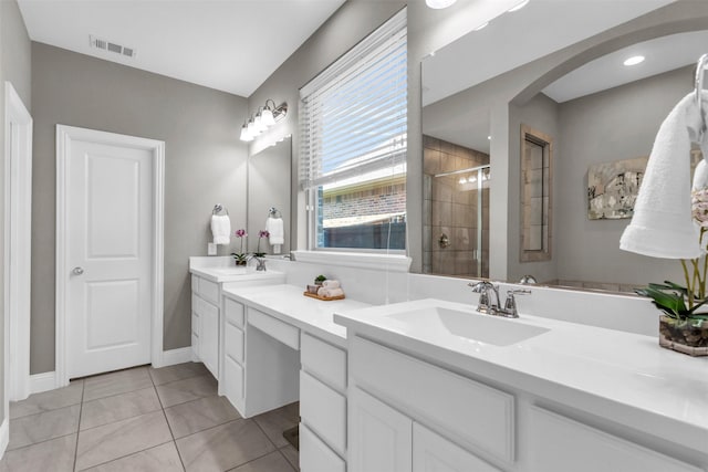 bathroom with double vanity, visible vents, a stall shower, and a sink