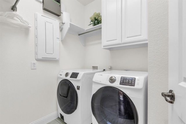 washroom featuring washer and dryer, baseboards, cabinet space, and electric panel