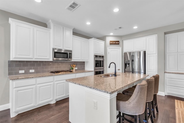 kitchen with dark wood-style flooring, stainless steel appliances, visible vents, and a sink