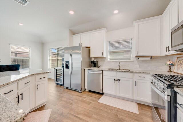 11225 Klondike Ln, Aubrey, TX 76227 - kitchen featuring light wood-style flooring, beverage cooler, a sink, backsplash, and appliances with stainless steel finishes