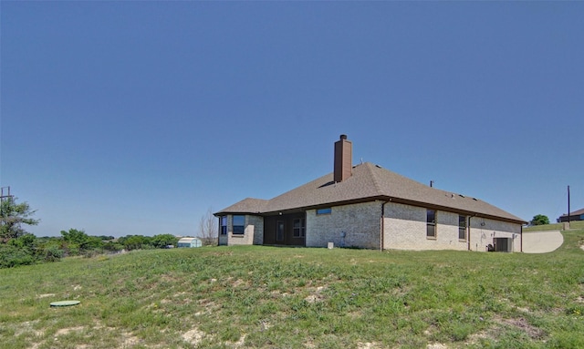 217 Timber Valley Ct, Weatherford, TX 76085 - back of house featuring a chimney, central AC unit, brick siding, and a yard
