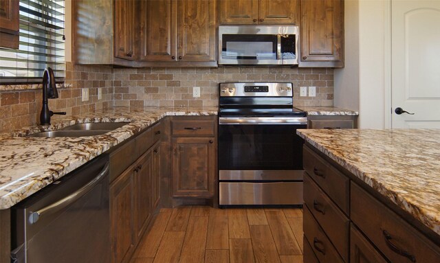 217 Timber Valley Ct, Weatherford, TX 76085 - kitchen with stainless steel appliances, a sink, wood finished floors, backsplash, and light stone counters