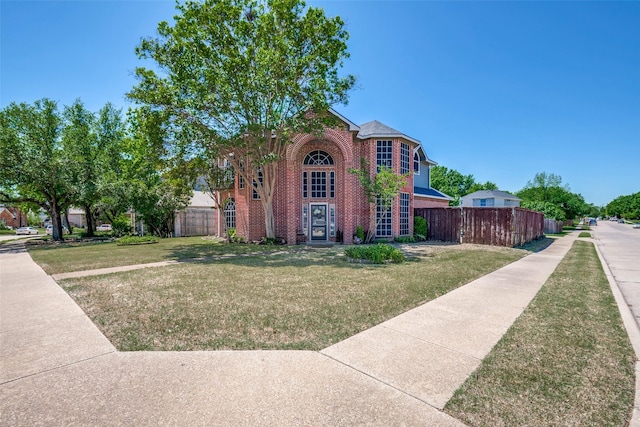 traditional home featuring fence, a front lawn, and brick siding