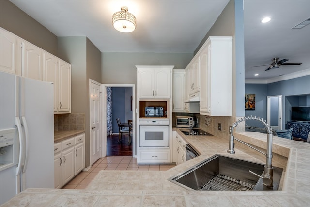 kitchen with white cabinets, backsplash, light tile patterned floors, a sink, and black appliances