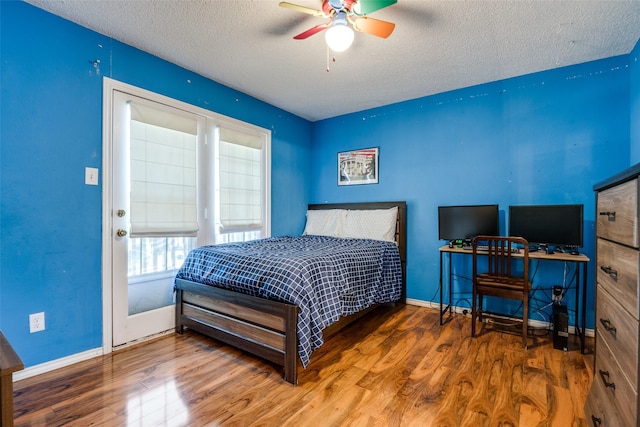 bedroom featuring wood finished floors, a textured ceiling, a ceiling fan, and baseboards