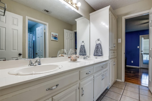 full bath with tile patterned flooring, visible vents, a sink, and a textured ceiling