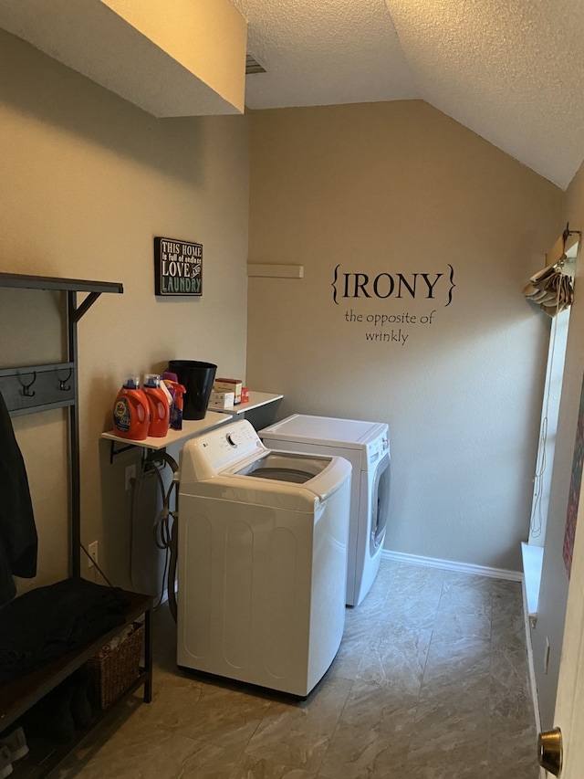 washroom with a textured ceiling, washer and clothes dryer, baseboards, and laundry area