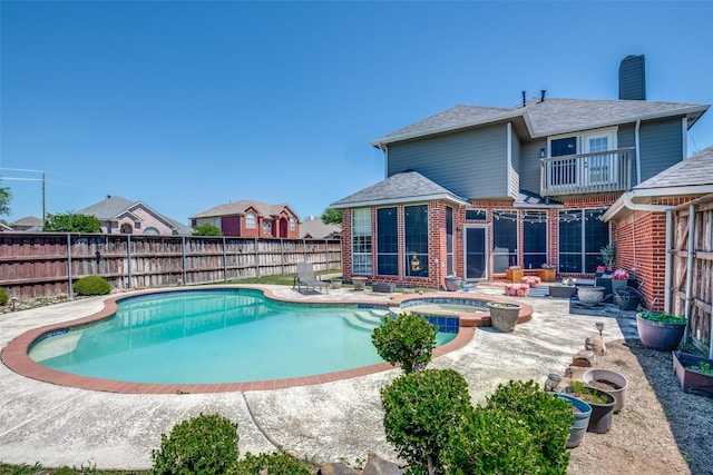view of pool with a patio area, a fenced backyard, a pool with connected hot tub, and a residential view
