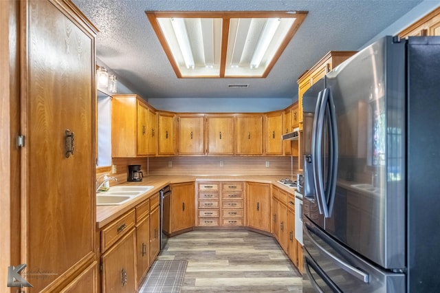 kitchen with light wood finished floors, a sink, visible vents, light countertops, and appliances with stainless steel finishes