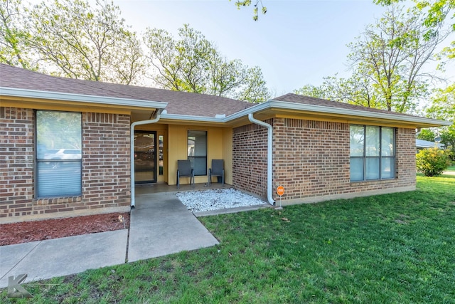 exterior space with a patio area, brick siding, and a yard