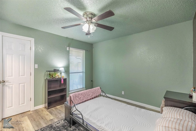bedroom featuring light wood-style flooring, baseboards, a textured ceiling, and ceiling fan