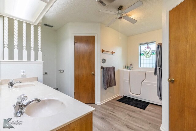 full bathroom featuring wood finished floors, visible vents, a sink, and a textured ceiling