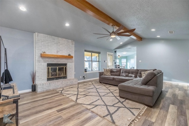 living area featuring wood finished floors, lofted ceiling with beams, ceiling fan, baseboards, and visible vents