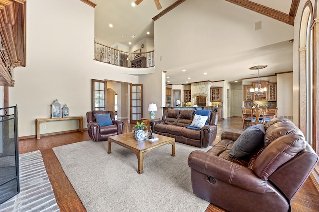 living room featuring recessed lighting, ornamental molding, baseboards, high vaulted ceiling, and a notable chandelier