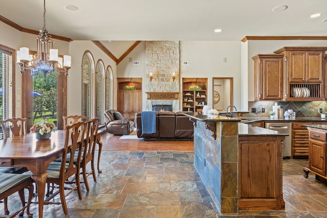 kitchen with an inviting chandelier, stainless steel dishwasher, ornamental molding, a peninsula, and brown cabinetry