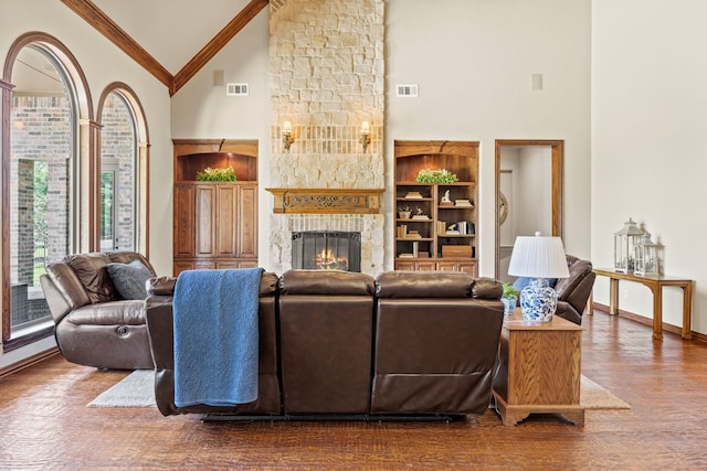 living room featuring high vaulted ceiling, a stone fireplace, wood finished floors, and visible vents
