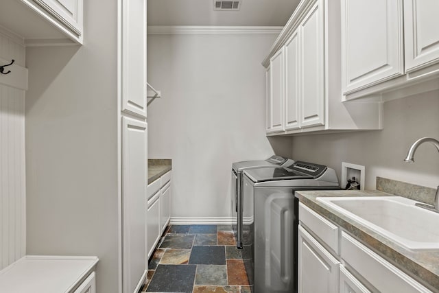 washroom with a sink, stone tile floors, baseboards, cabinet space, and washer and dryer
