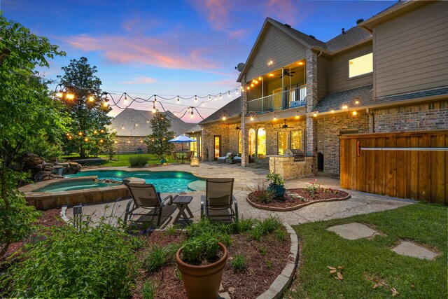 pool at dusk featuring fence, a patio area, a ceiling fan, and a pool with connected hot tub