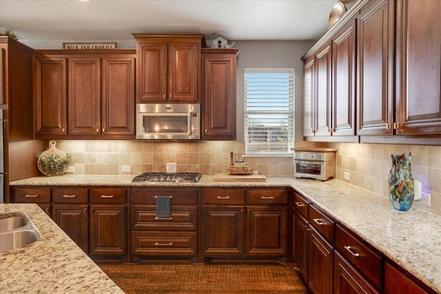 kitchen featuring tasteful backsplash, appliances with stainless steel finishes, and light stone counters