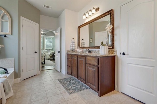 bathroom featuring baseboards, visible vents, tile patterned flooring, a garden tub, and vanity